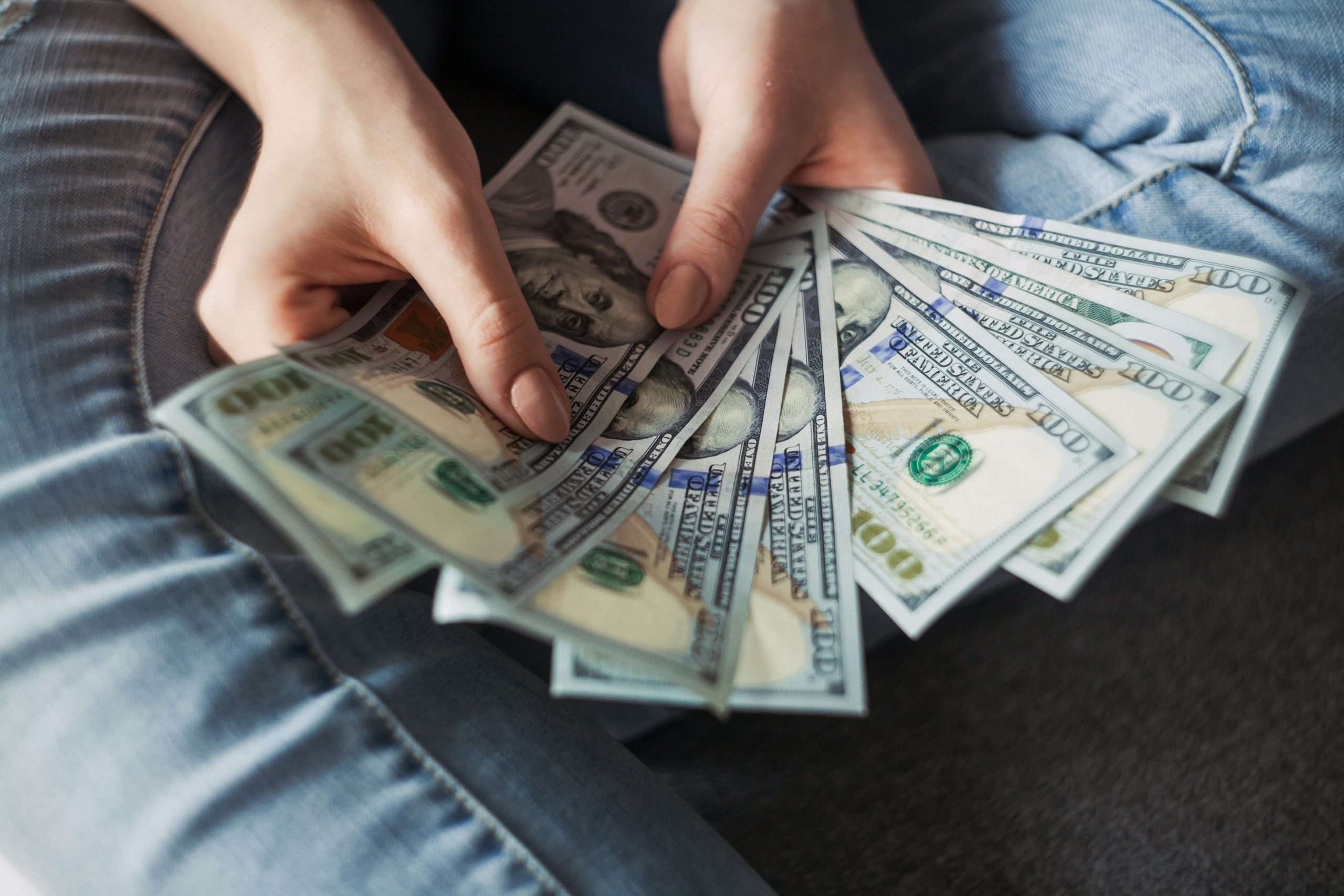 hands holding fanned $100 bills
